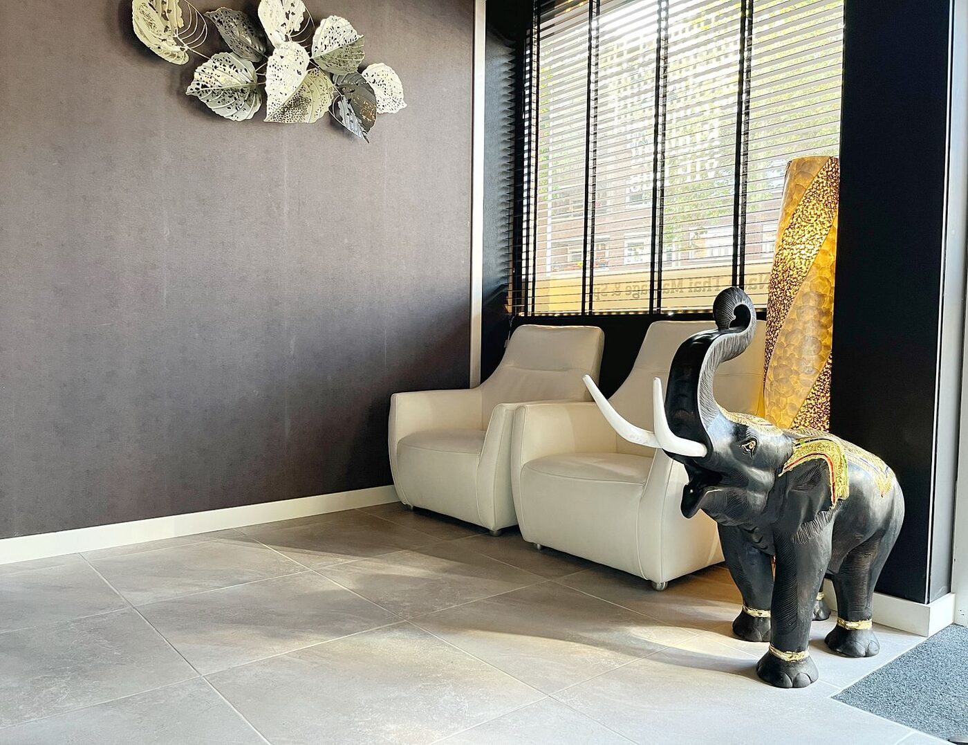 The reception of Nada Thai Massage in Eindhoven — purple sofa and traditional Thai statues
