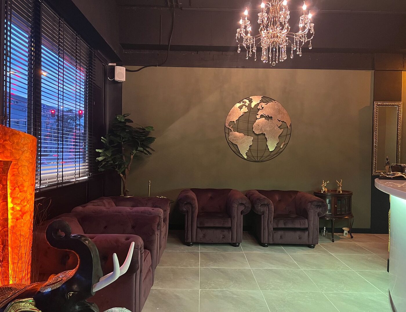 Lounge area with crystal chandelier, world-map art and chesterfield sofas